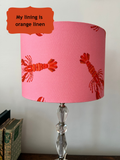 Drum shaped lampshade with orange and red lobsters. a speech bubble in the top left of the shade says 'My lining is orange linen'