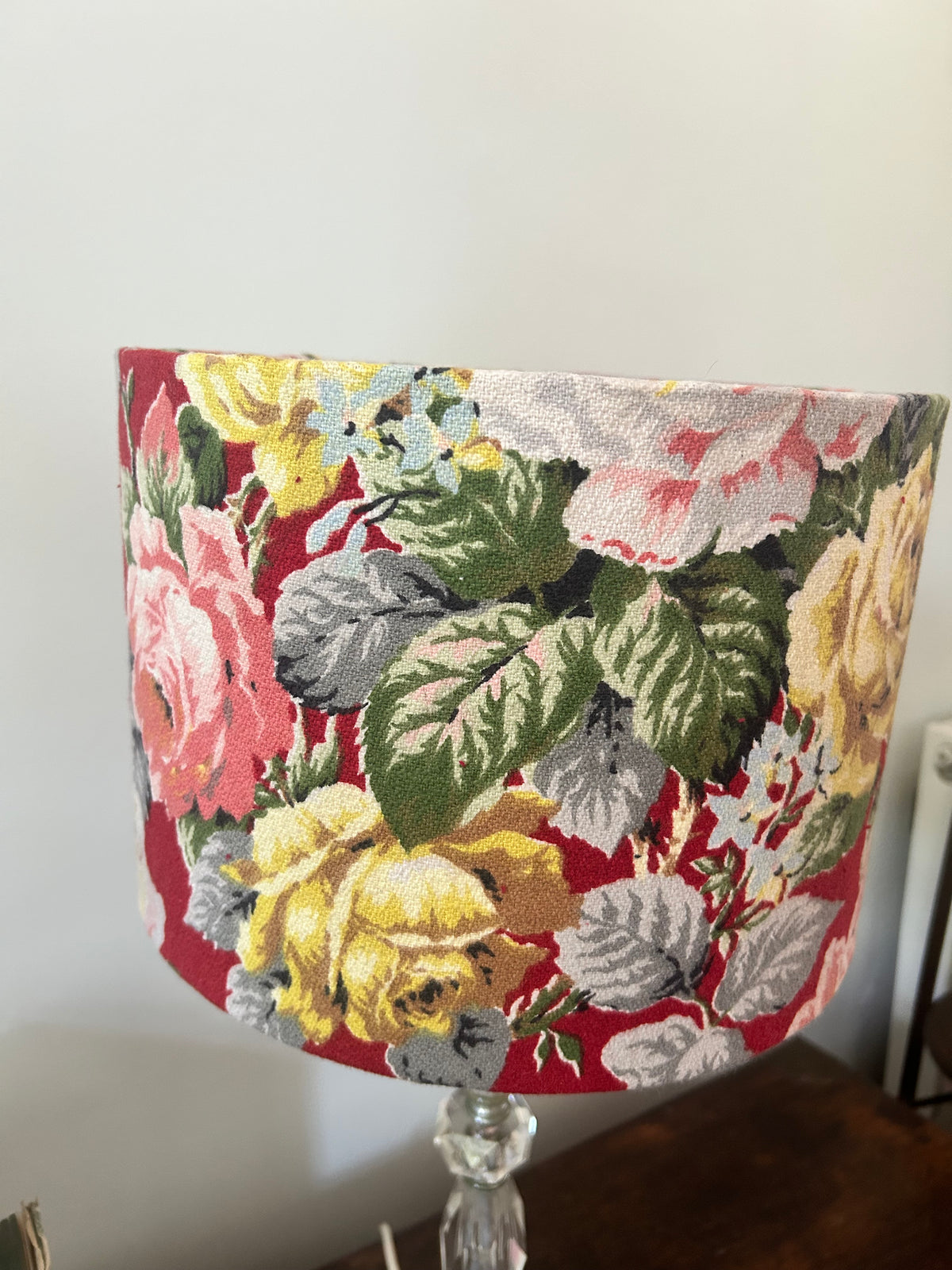 Vintage rose drum lampshade showing pink and yellow roses with green and grey leaves on a red background.