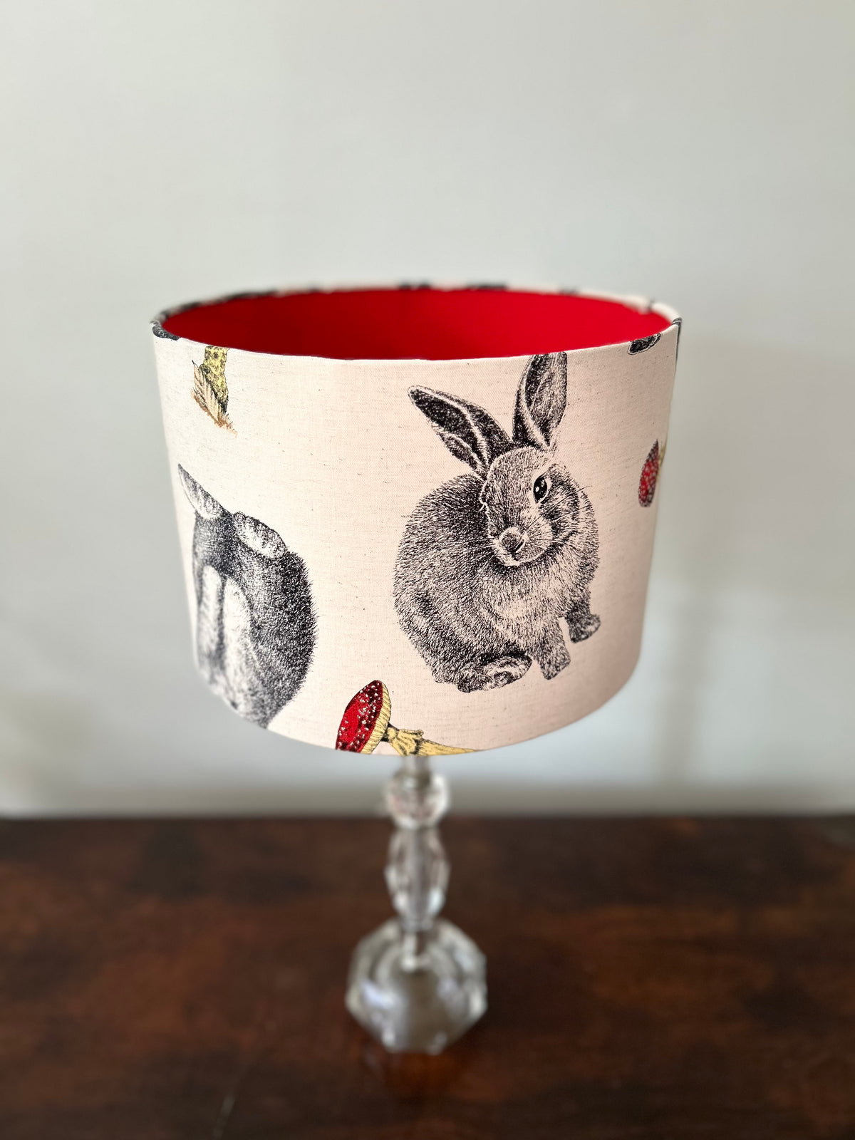 Woodland rabbit drum lampshade viewed from above, showing its red lining, detailed rabbit illustrations and red toadstools.