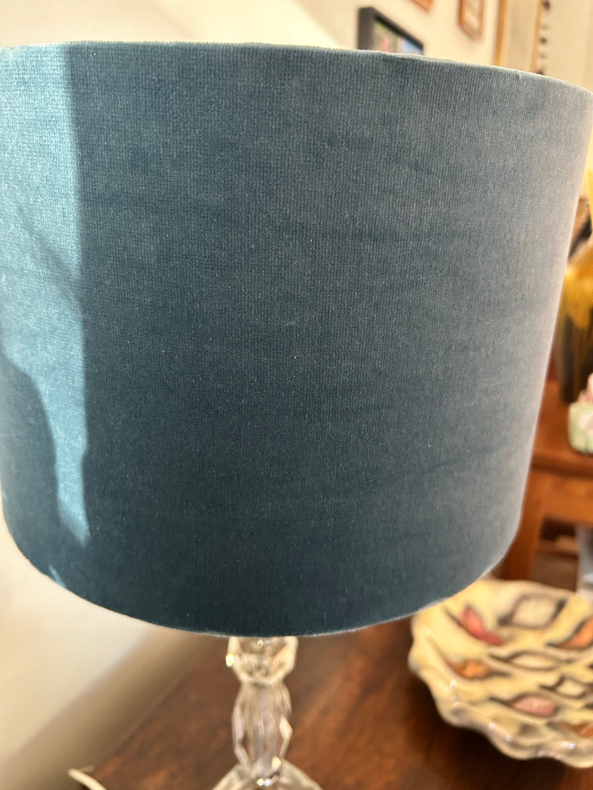 Side view of the blue velvet drum lampshade on a clear glass lamp base.