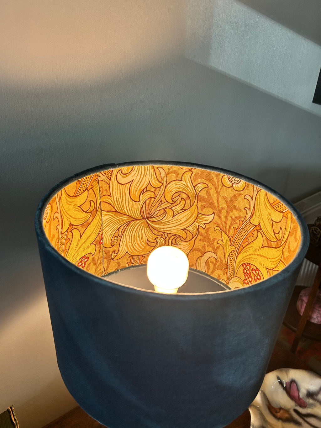 Close-up inside the lit lampshade showing the golden floral lining and bulb.