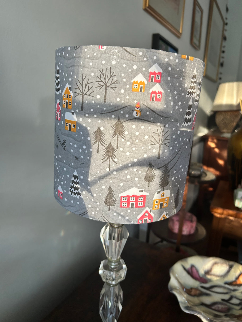 Side view of the grey snowy village lampshade showing colourful cottages, bare trees and a snowman.