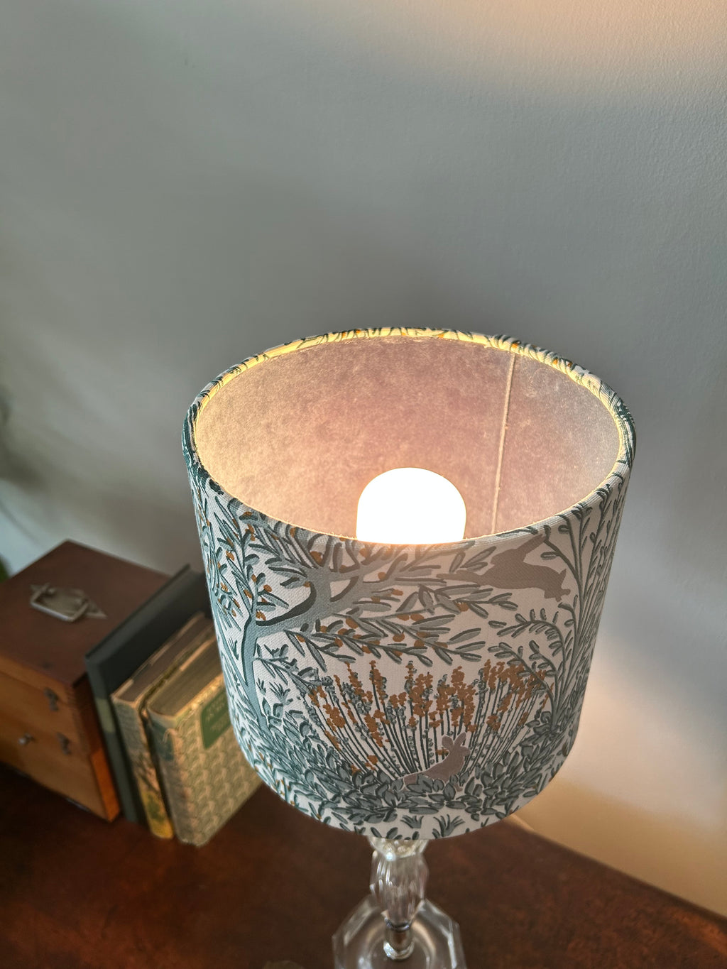 Rabbit-print drum lampshade viewed from above with the bulb lit and lining illuminated.