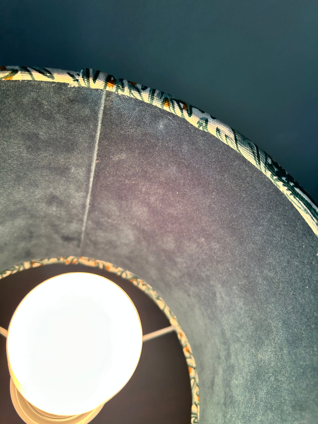 Close-up inside the illuminated lampshade showing the velvet lining, seam and patterned fabric rim