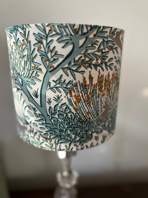 Woodland rabbit drum lampshade with grey rabbits, teal branches and gold details on a white background.