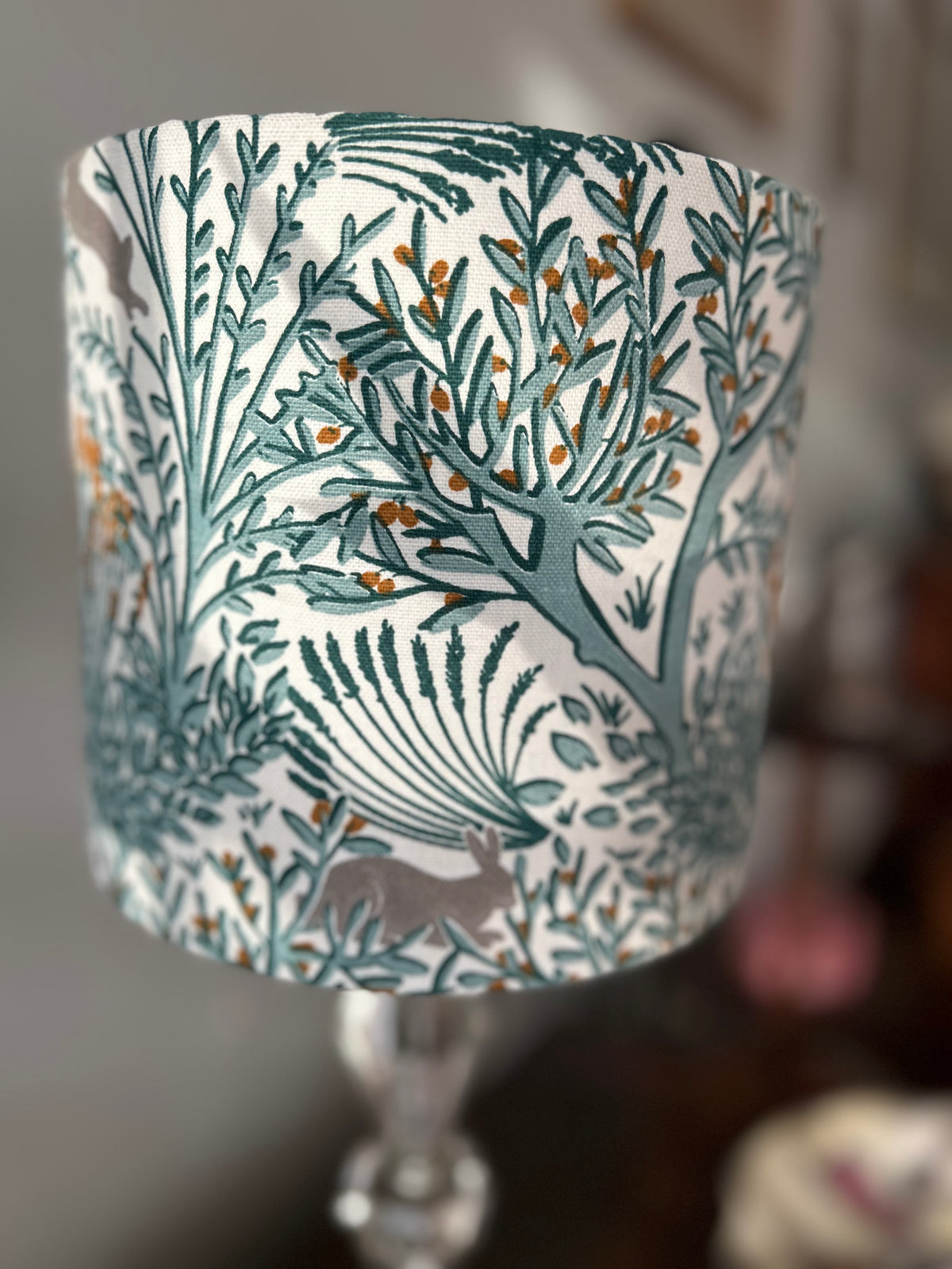 Side view of the lampshade fabric showing grey rabbits among teal branches and small gold accents.
